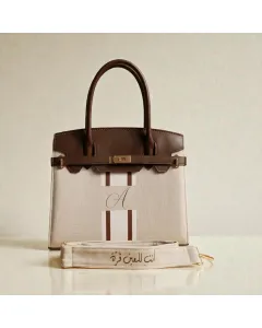 شنطة / حقيبة يد بخطوط فنية قابلة للتخصيص – اسم أو أحرف – صنع في الأردن – قماش فاخر مع بطانة جلد – حجم صغير (25×21×10 سم) / كبير (32×27×12 سم) – ألوان متعددة